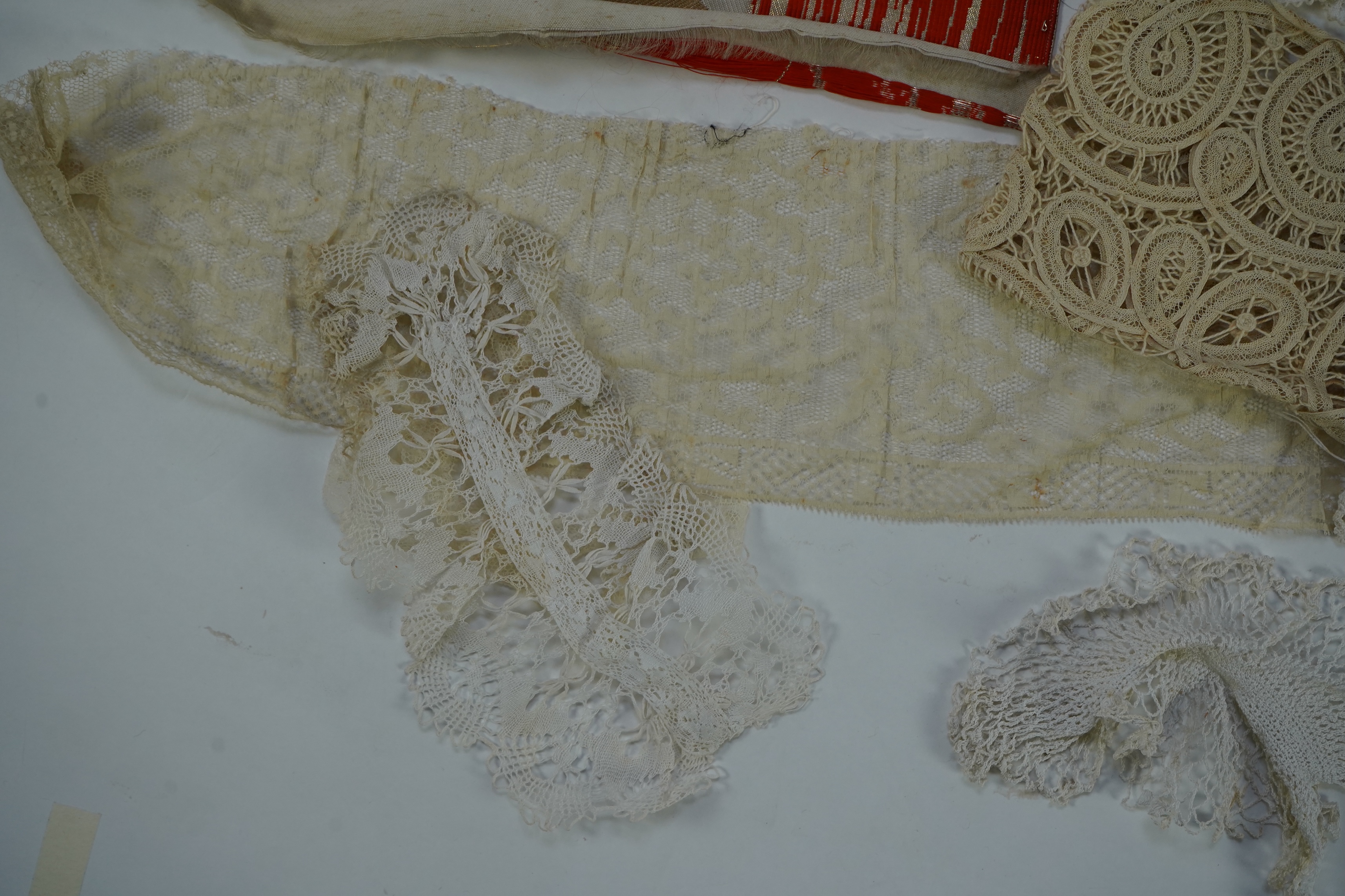 A collection of mixed machine lace: a black lace stole, two black veils, a sample of Japanese brocade, a length of metallic ribboning and various items of cream lace, ribboning 230cm long. Condition - variable poor to fa